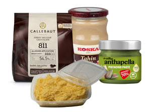 A collection of gourmet chocolate making ingredients including a bag of Callebaut dark chocolate, a jar of KOSKA tahini, a container of Anthap natural pistachio paste, and Anthap fresh shredded wheat.
